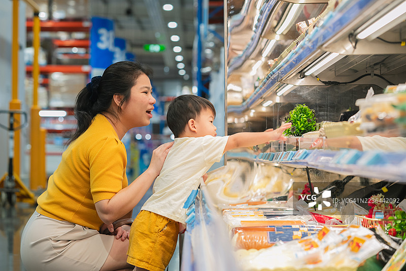 快乐的亚洲母亲和儿子在百货商店的杂货店享受亲子购物之旅。幼儿一起挑选食品和消费品，营造出一个幸福的亚洲家庭出游时光。图片素材