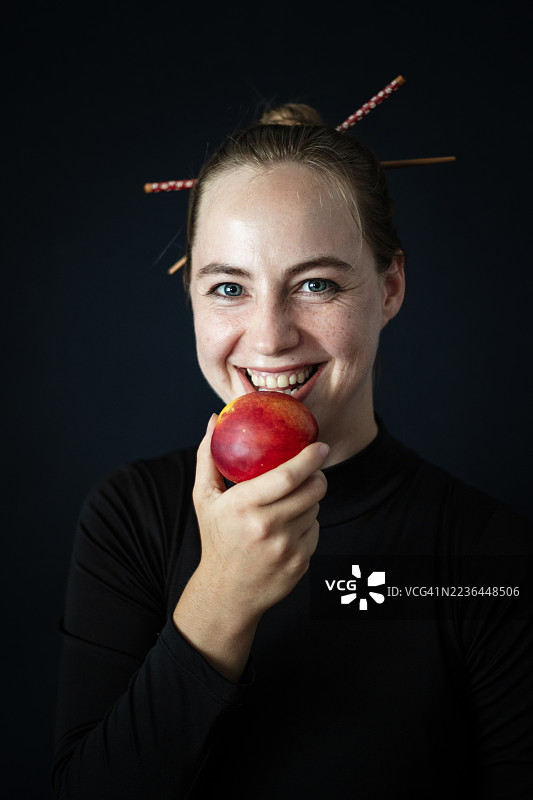 金发女性肖像，正在吃油桃。图片素材