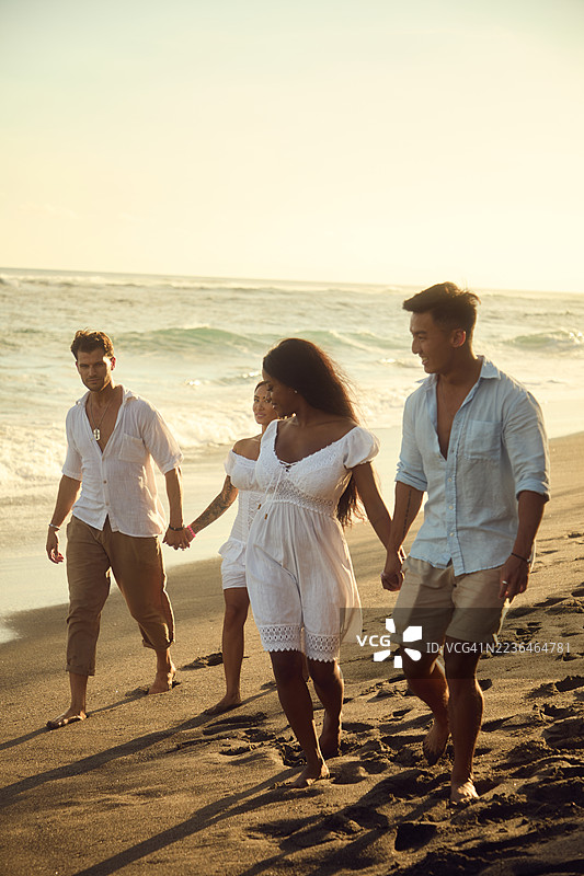 一群朋友在阳光明媚的海滩上散步，享受轻松的时光。图片素材