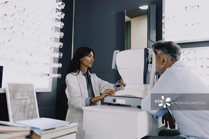 女眼科医生在现代眼科诊所使用诊断设备为一位老年男性患者进行眼部检查。图片素材