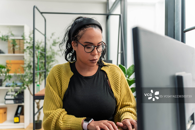 一位专注的非裔拉丁裔研究员在现代工作空间分析数据图片素材