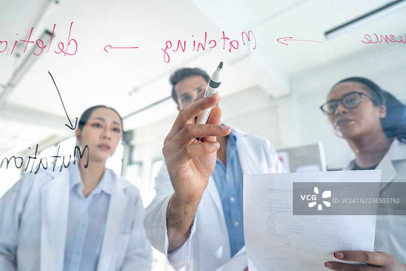 多元化研究团队在现代实验室的玻璃板上分析数据图片素材