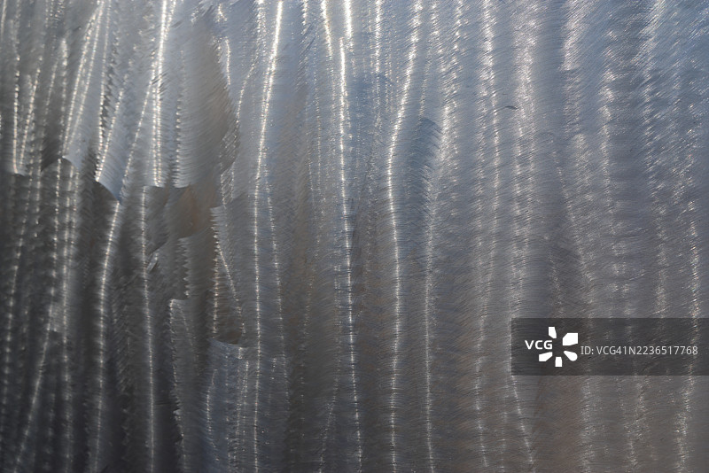 光滑的不锈钢金属表面，带有随机波浪状的拉丝纹理图片素材