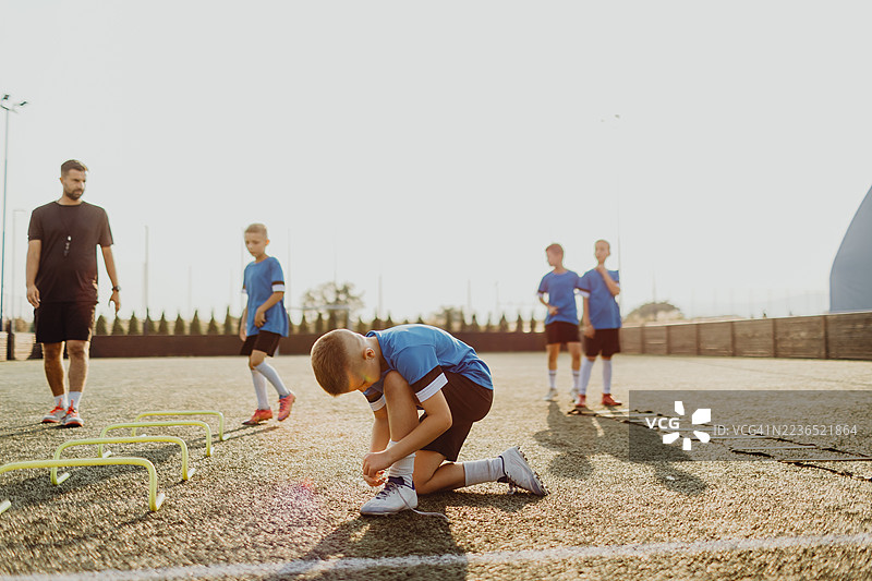 一群男孩在足球场上训练时跳过障碍物图片素材