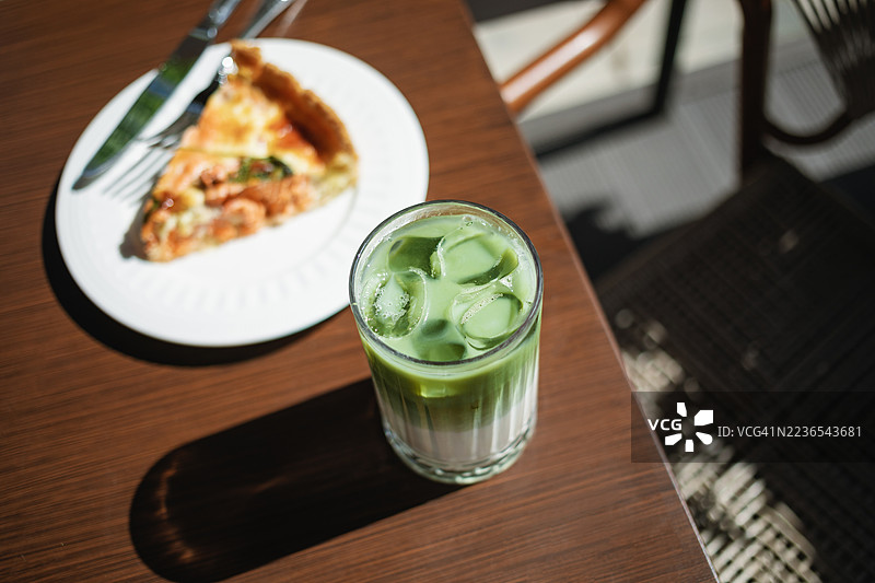 夏季户外咖啡馆的冰抹茶拿铁特写和一片三文鱼咸派图片素材