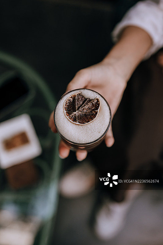 手握鸡尾酒，配有干燥柑橘装饰图片素材