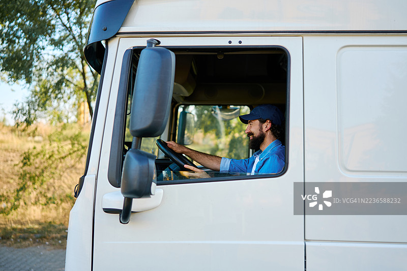 微笑的卡车司机在长途驾驶中掌舵图片素材