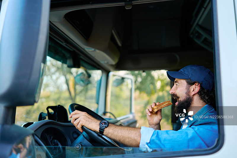 卡车司机在驾驶卡车时吃三明治图片素材