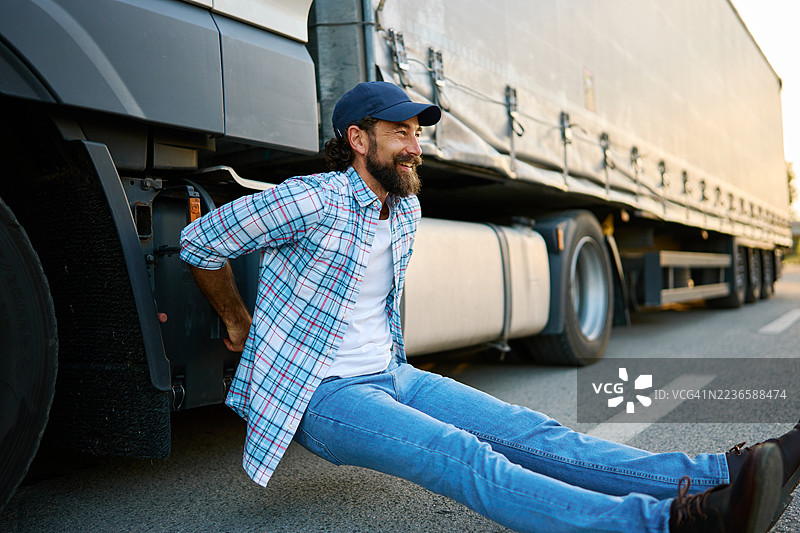 快乐的卡车司机在他的半挂车旁锻炼图片素材