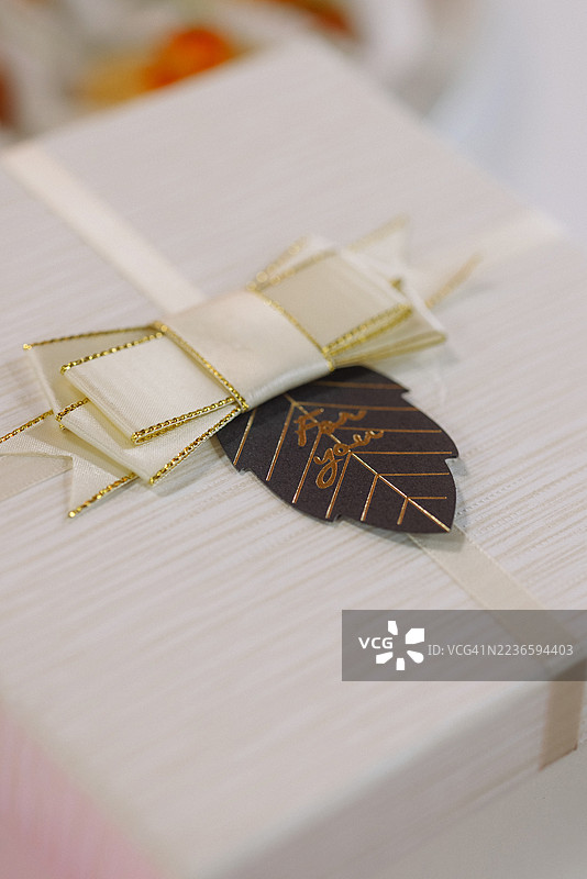 柔软背景上带有丝带和金箔标签的优雅白色礼品盒图片素材