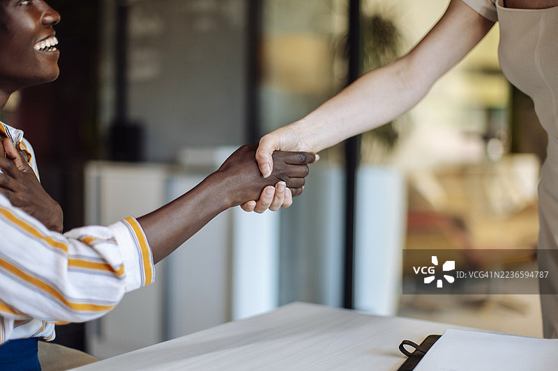 同事之间的握手，强调办公室环境中的团队合作与专业精神图片素材