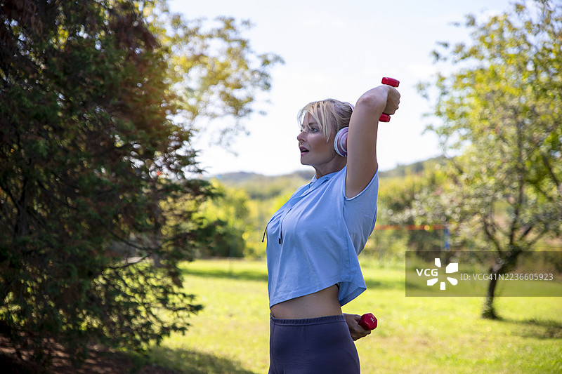 女性在户外使用哑铃锻炼图片素材