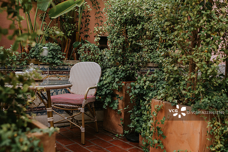 宁静花园中被郁郁葱葱的绿植和装饰性瓷砖环绕的舒适户外座位区图片素材
