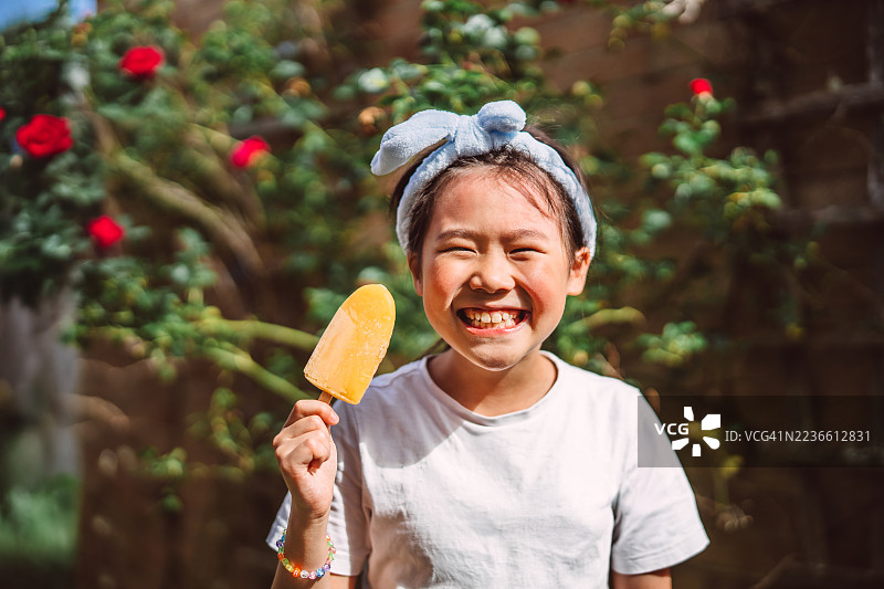 快乐的孩子在阳光明媚的夏日户外享受橙色冰棒图片素材