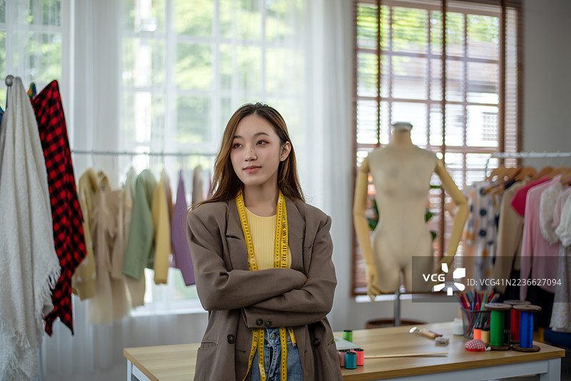 一位快乐美丽的年轻女性，穿着休闲的设计师，坐在家里的桌子旁。图片素材