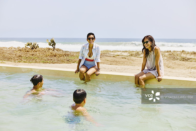 家庭在海滩度假期间享受度假村游泳池的宽景镜头图片素材