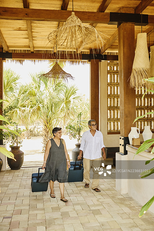 一对老年夫妇带着行李抵达豪华度假酒店大堂的广角镜头图片素材