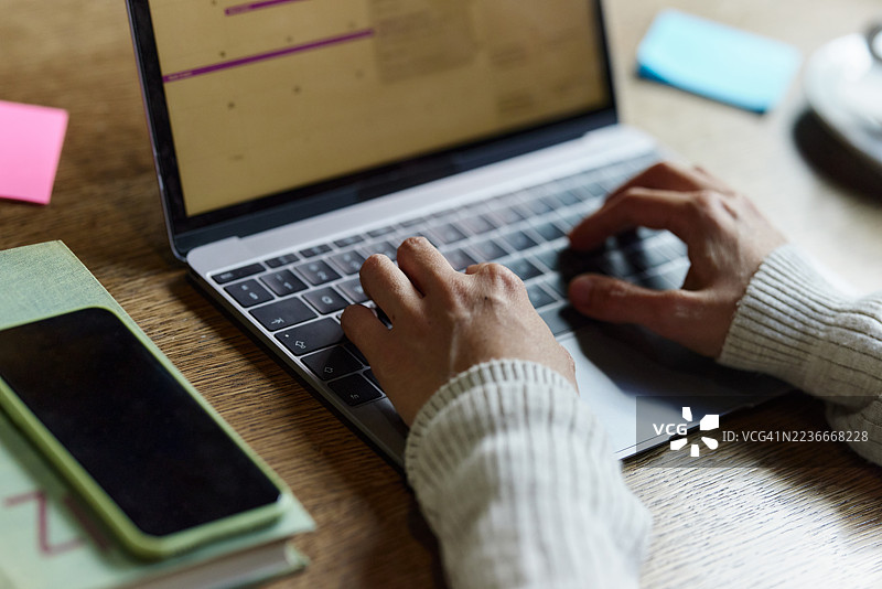 办公室里一位女性在笔记本电脑上工作的特写镜头。图片素材