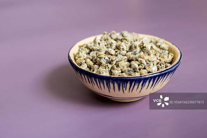 一碗煮熟的小蛤蜊，背景为紫色图片素材