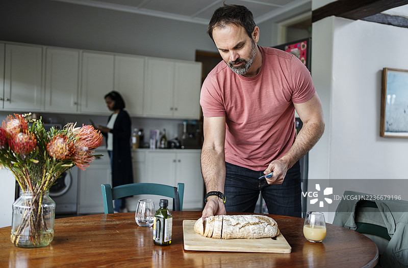 男人在家里的早餐桌上小心翼翼地放下面包图片素材