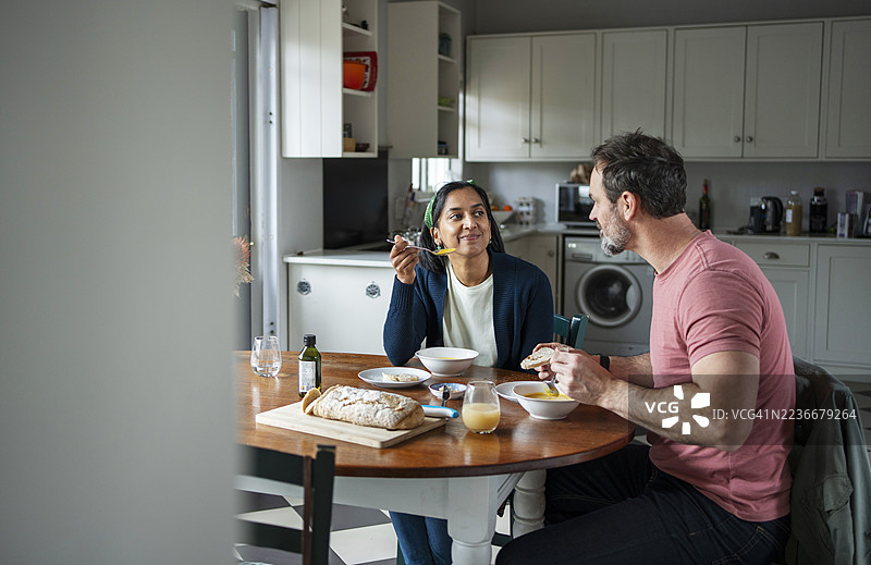 夫妻俩在厨房家里的圆形木桌旁享用午餐图片素材