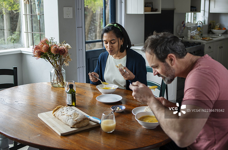 一对夫妇在家里的木桌上享用自制的汤和面包作为午餐图片素材