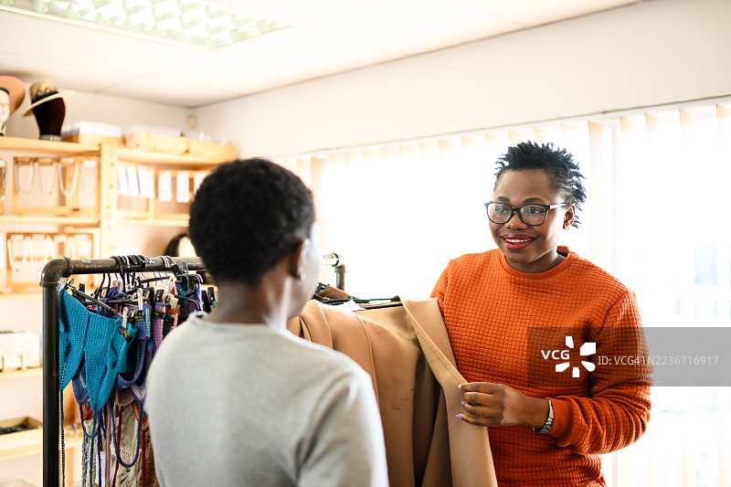 一位快乐的顾客在当地精品店里与女性店主讨论服装购买事宜图片素材