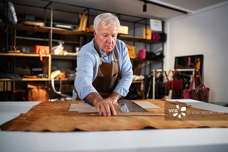 资深工匠在工作坊中精心制作皮革制品，展现出精准与专注。图片素材
