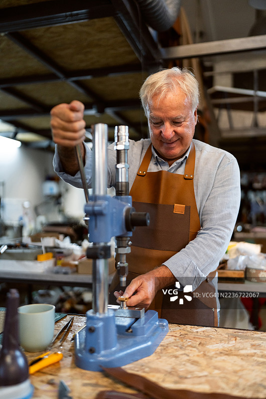 老练的工匠在工作坊中使用铆钉制作皮革制品图片素材