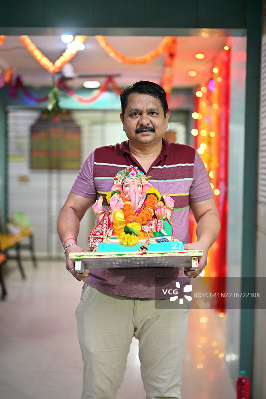 男子在为甘尼什节搬运装饰好的甘尼什神像图片素材