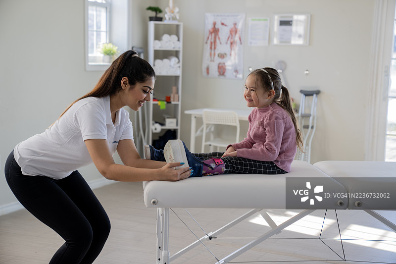 拉丁裔物理治疗师在诊所帮助亚洲女孩使用假肢，友好的治疗课程图片素材
