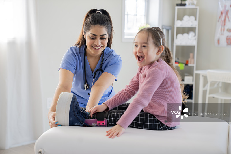 亚洲女性护士协助年轻女孩进行肢体强化物理治疗课程图片素材