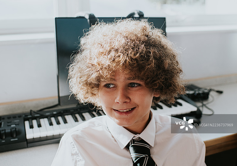 教室环境中一位年轻青少年的肖像，拥有卷曲的头发。图片素材