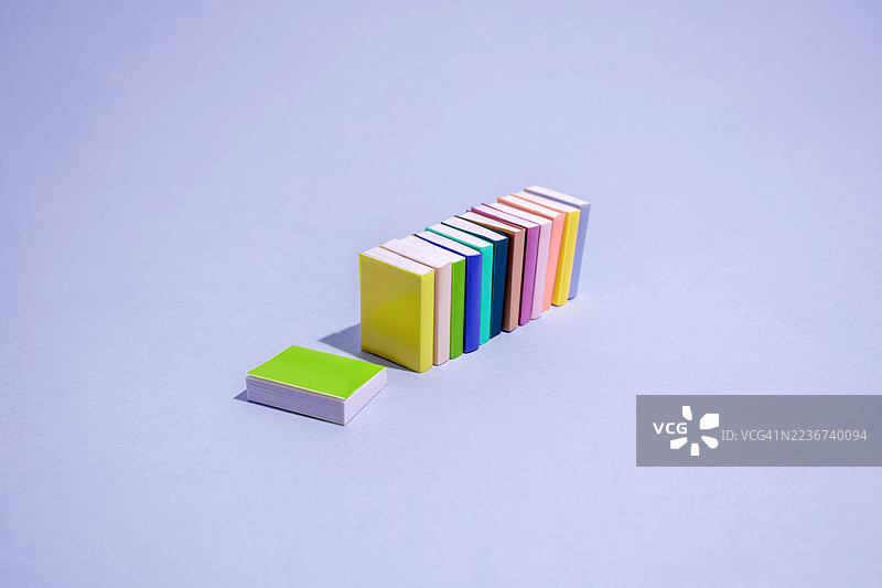 色彩斑斓的书本在浅紫色背景上竖立和躺着图片素材