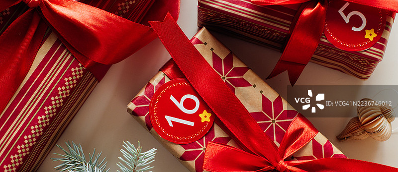 带有编号的圣诞节礼物和节日装饰品、冷杉树枝的日历标签，背景为浅色，俯视平铺。图片素材