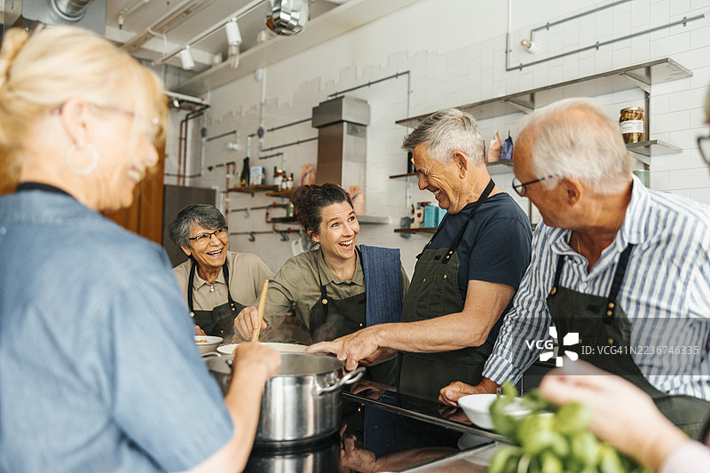 老年学生在商业厨房里与厨师一起享受烹饪乐趣图片素材