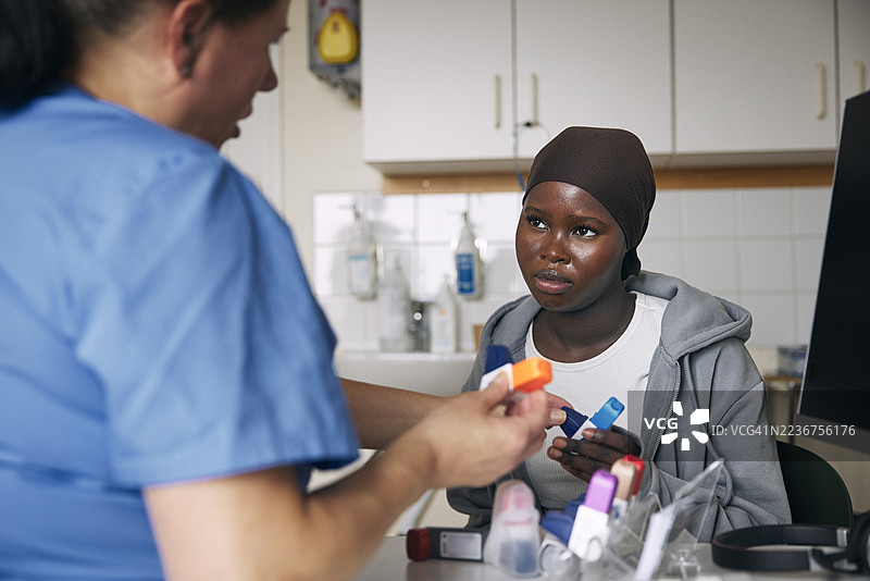 女性医疗专家在诊所向青少年女孩讲解哮喘吸入器的使用方法图片素材