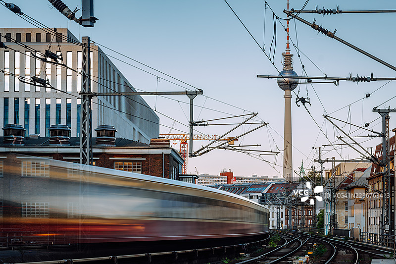 柏林城市铁路：模糊的地铁在高架电缆下的轨道上，背景是电视塔图片素材