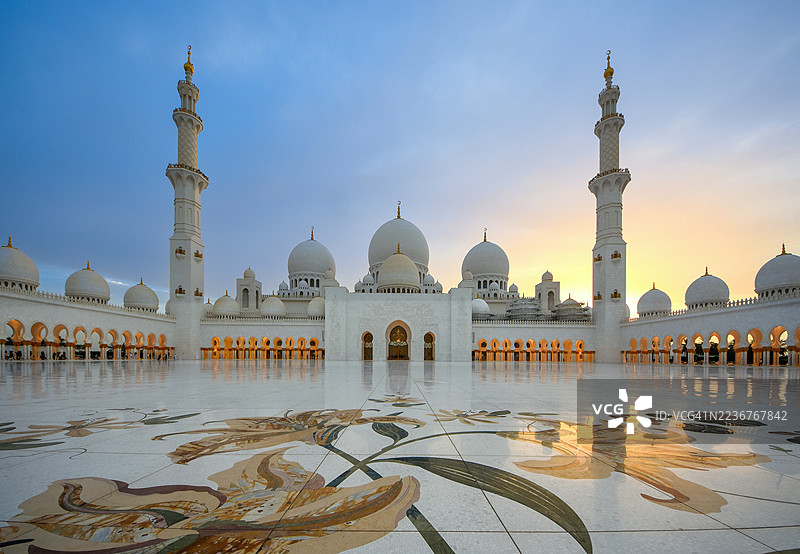 阿布扎比扎耶德清真寺外观，背景为宏伟的柱廊和日落，位于阿联酋图片素材