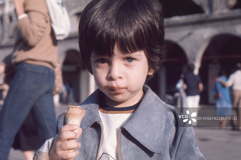 1977年，意大利威尼托大区帕多瓦，一位三岁孩童吃着巧克力冰淇淋，满嘴都是巧克力酱的复古照片图片素材