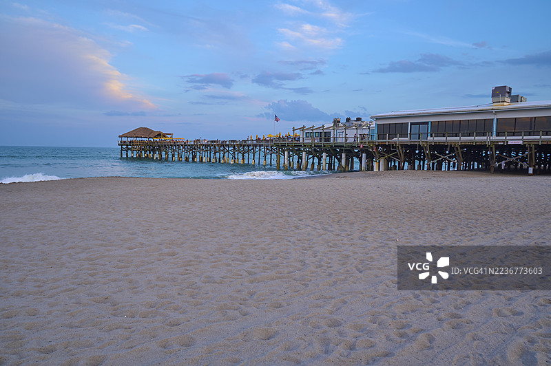 晴朗的天空下，木板栈道延伸入蓝色大海，沙滩上，西盖特可可海滩栈道，佛罗里达州可可海滩港（美国）图片素材