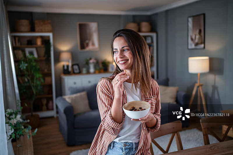 微笑的年轻女性在家享用健康小吃图片素材