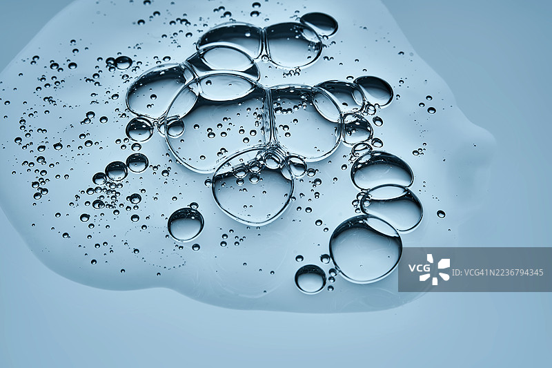 清晰水滴和气泡特写在浅蓝色表面上，形成抽象而清新的背景图片素材