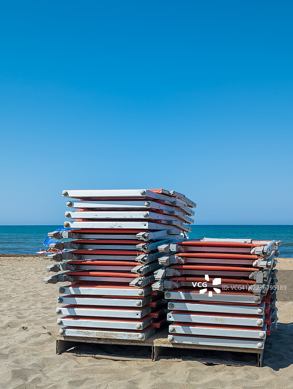 沙滩上堆叠的沙滩椅，背景是大海和晴朗的蓝天，意大利菲乌米奇诺，辛吉塔图片素材