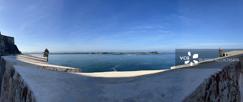 从历史悠久的堡垒墙上俯瞰海洋和远处的海岸线，蓝天晴朗，地点：圣胡安，美国，圣费利佩·德尔莫罗城堡图片素材