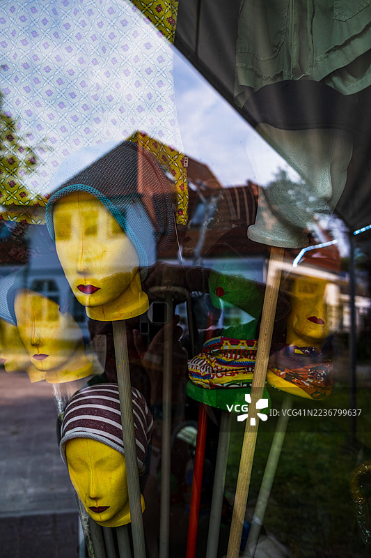 带帽子的模特头在商店橱窗中反射，展示零售陈列和城市倒影图片素材