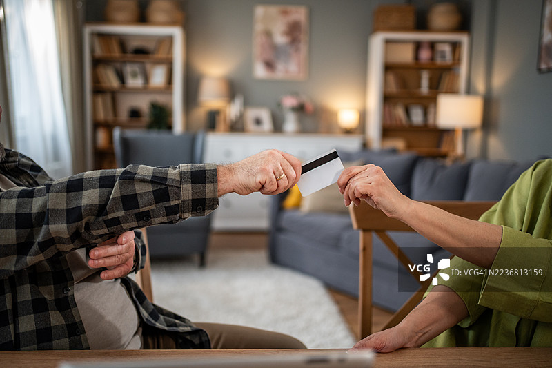 老年夫妇在进行在线交易时交换信用卡图片素材
