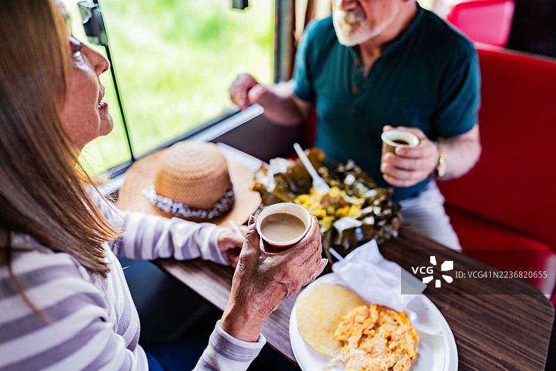 close-up of a senior woman drinking coffee with husband during breakfast on tourist train图片素材