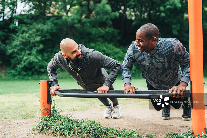 两个朋友在户外健身房一起锻炼图片素材