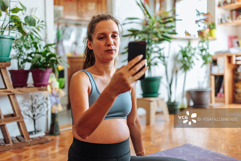 孕妇在家中进行锻炼，视频通话中。图片素材